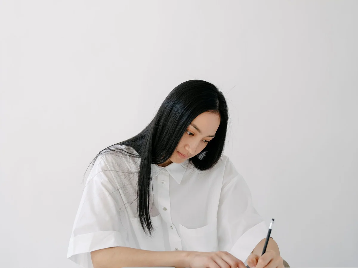 Woman writing a short Sunday evening plan at a kitchen table